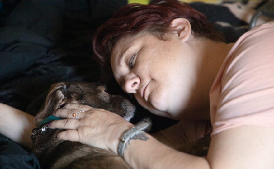 Army veteran AJ Williams lies in bed with her dog Sherlock at her home in El Cajon, May 27, 2020.