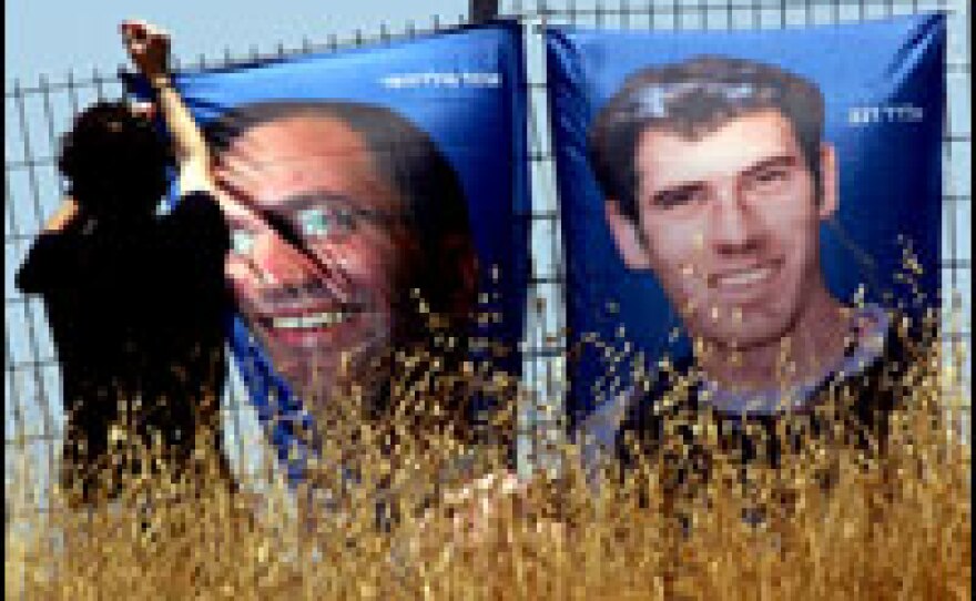 An Israeli hangs posters of the two Israeli soldiers, Eldad Regev (right) and Ehud Goldwasser (left), held by Hezbollah in Lebanon. Since their capture, posters such as this one were ubiquitous in Israel.