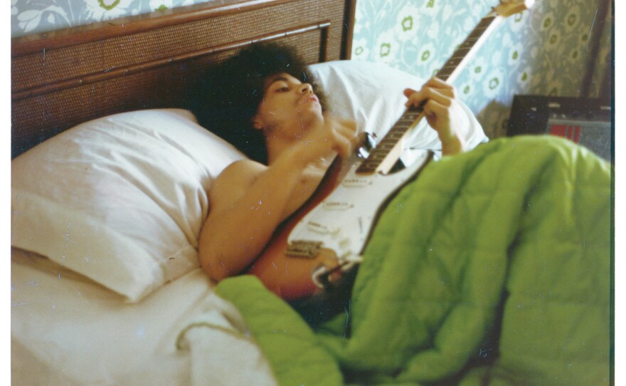 Prince plays a guitar in bed at his new home on France Avenue, April 1978.