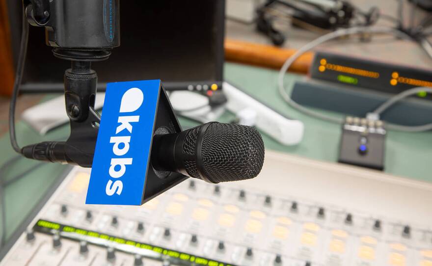 Photo of podcast studio with branded microphone on top of desk with KPBS logo