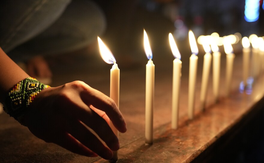 Activists light candles as they condemn the killing of Filipino journalist Percival Mabasa during a rally in Quezon, Philippines, Tuesday Oct. 4, 2022.