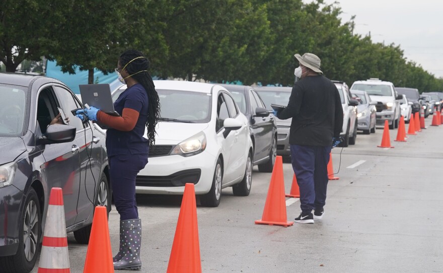Employees of Nomi Health check in a long line for COVID-19 tests Tuesday in North Miami, Fla. The omicron variant has unleashed a fresh round of fear and uncertainty for travelers, shoppers and party-goers across the U.S.
