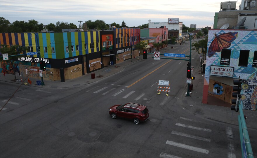 A car drives by boarded-up businesses as it crosses Lake Street in Minneapolis. Volunteers, sometimes armed, are working together to protect homes and businesses.