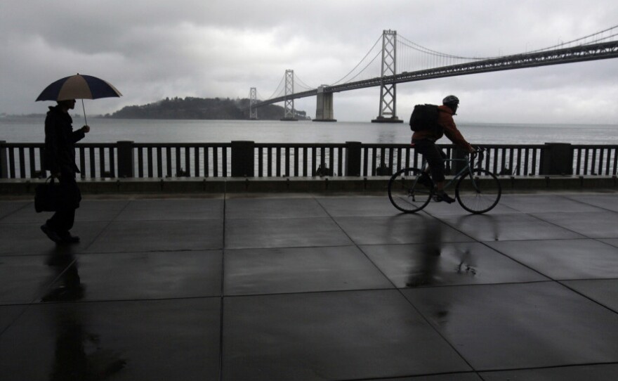 A pedestrian and cyclist are seen along the <a href="http://www.sfgate.com/cgi-bin/article.cgi?f=/c/a/2004/10/17/MNCITY1_TIMELINE.DTL">Embarcadero</a> with the San Francisco Oakland Bay Bridge in the background. San Francisco dismantled a freeway in this location in the early 1990s.
