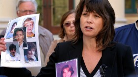 Mary Grant (R), who was allegedly molested by her priest when she was a child, shows a group of photos of abuse victims that have committed suicide due to sexual abuse by catholic clergy, during a vigil to bring attention to victims of sexual abuse by religious leaders within the Catholic church on March 1, 2007 in San Diego, California. 