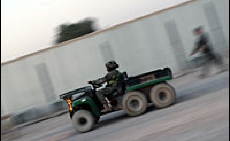 A U.S. soldier drives a six-wheeled Gator on one of the main roads through the base.  All kinds of vehicles, from tanks to pickup trucks, share the road.