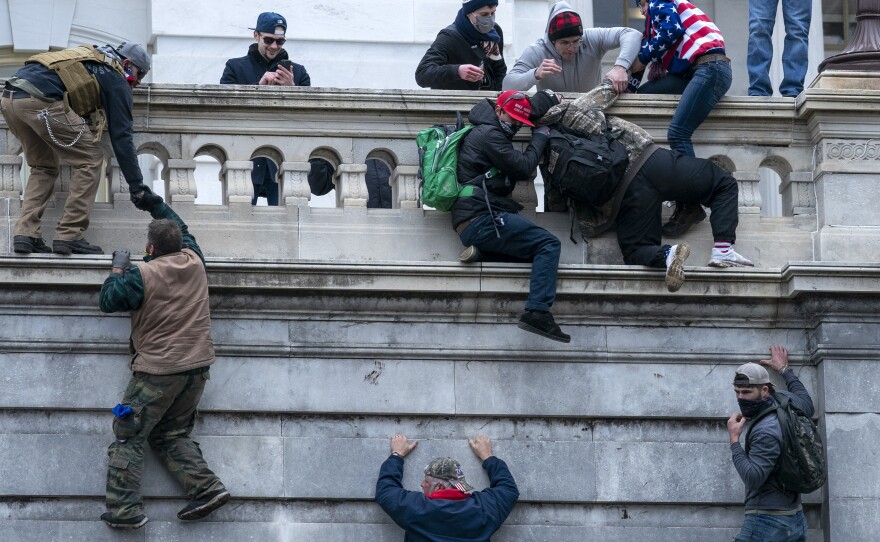 Insurrectionists climb the west wall of the the U.S. Capitol, Jan. 6, 2021, in Washington.