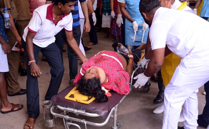An injured Sri Lankan woman lies on a stretcher as hospital workers transport her at the District General Hospital in Negombo, following the explosion at St. Sebastian's Church.