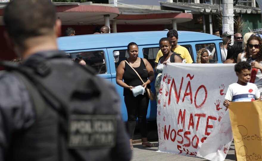 Protesters hold a sign Saturday that reads, in Portuguese, "Don't kill our children," in a march against police and gang conflicts that have left residents of the Complexo de Alemao favela in the crossfire.