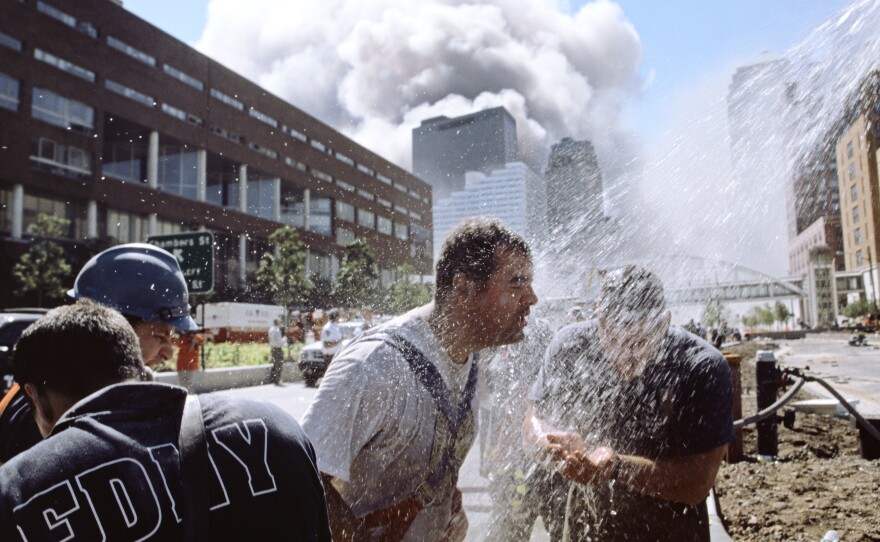 Rescue workers clean off on the West Side Highway as smoke billows into the clear blue sky.