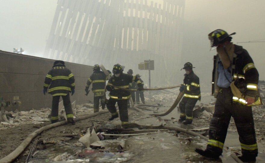 Firefighters work beneath the vertical struts of the World Trade Center's twin towers, in Lower Manhattan, following the attacks of Sept. 11, 2001.