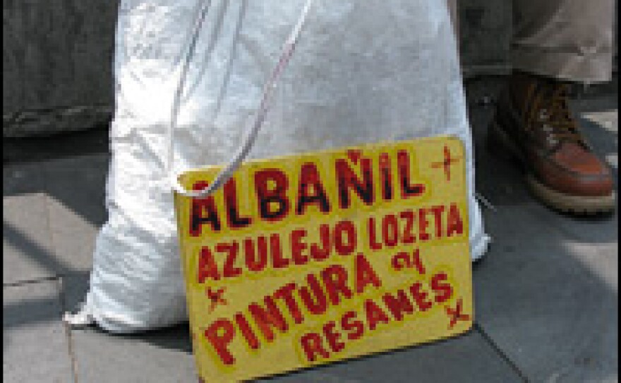 A laborer looking for work in Mexico City displays a sign touting his skills as a mason, a tile worker and a painter.