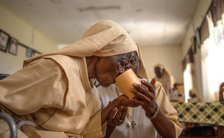 Sister Mary Consolata Nakawooja assists an elderly nun as she takes tea at the Little Sisters of St. Francis premises in Nkokonjeru, Uganda.
