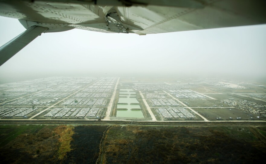 A plane flies over the U.N. Protection of Civilians site near Bentiu, South Sudan, home to more than 120,000 people. The drainage ponds in the middle of the camp were dug to prevent the kind of massive flooding that inundated the camp in 2014.