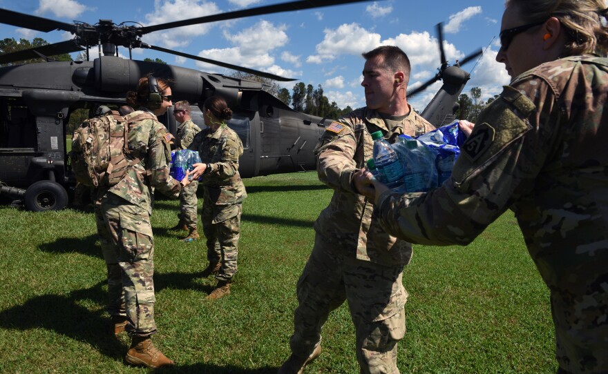 U.S. Army servicemen and women distribute water bottles and supplies.