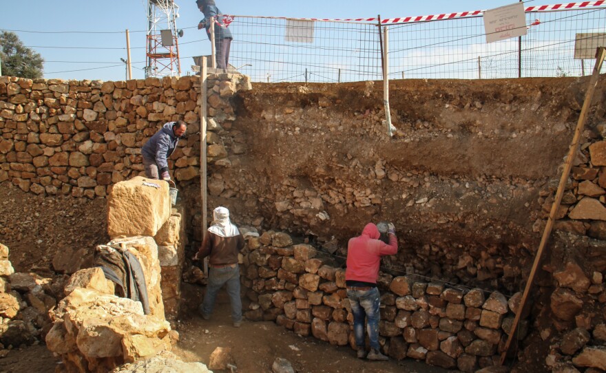 Palestinian workers employed by the Israeli army's archaeology unit lay cement to reinforce a row of stones, preparing the site as a tourist destination.