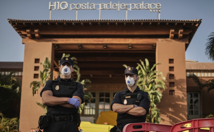 Police officers wear face masks Wednesday in front of a hotel on Tenerife, the largest of Spain's Canary Islands. Spanish officials say a hotel on the island has been placed under quarantine after an Italian doctor staying there tested positive for the new coronavirus.