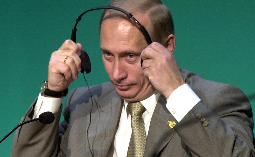 Russian President Vladimir Putin puts on his headset to listen to questions from delegates at a business forum on the side of the Asia-Pacific Economic Cooperation (APEC) summit in Bandar Seri Begawan, Brunei, on Nov. 15, 2000.