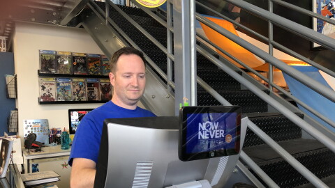 Aaron Trites is the owner of Now or Never Comics, which has the distinction of being within walking distance of Comic-Con. Trites is shown working behind the cash register on July 16, 2023.