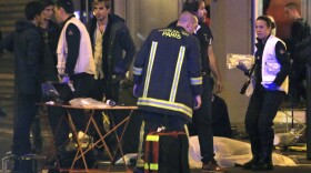 Rescue workers are shown at the scene as victims lay on the pavement outside a Paris restaurant, Nov. 13, 2015.