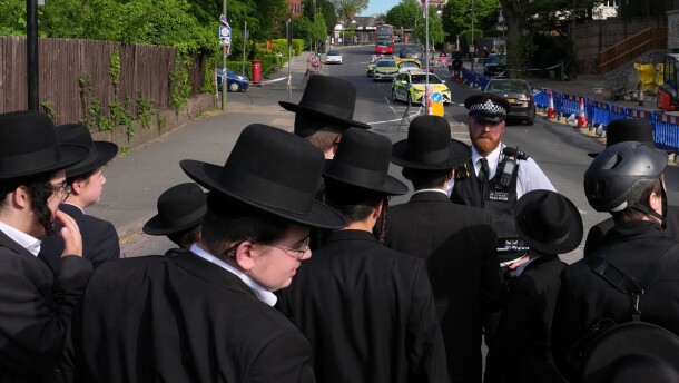 Members of the community watch as forensic officers search the area after two people were stabbed in the Golders Green neighborhood, that has a large Jewish community, in London, Wednesday.