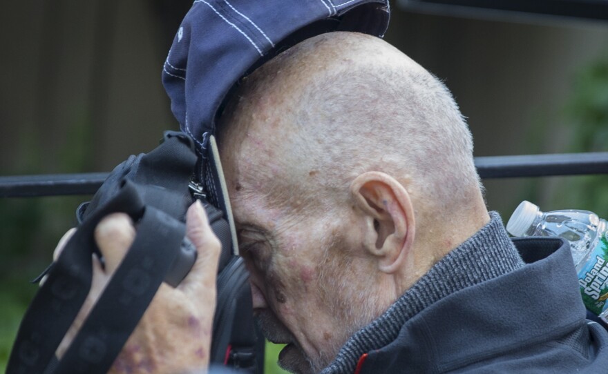 Irwin Lipkin, one of Bernard Madoff's longest-serving employees, covers his face as he is pushed in a wheelchair leaving U.S. court in New York on Wednesday.
