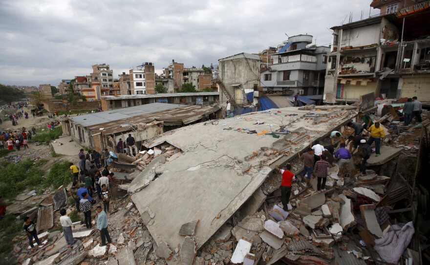 People gather near a collapsed house after a major earthquake in Kathmandu, Nepal.