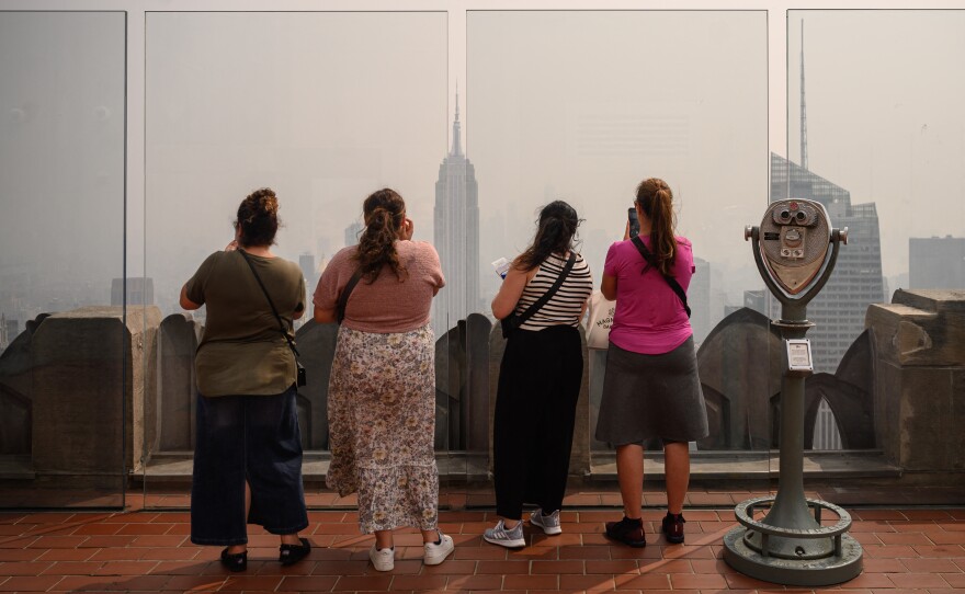 People at a viewing deck of the Rockefeller Center gaze at the Manhattan skyline on Friday during heavy smog brought by wildfire smoke from Canada.