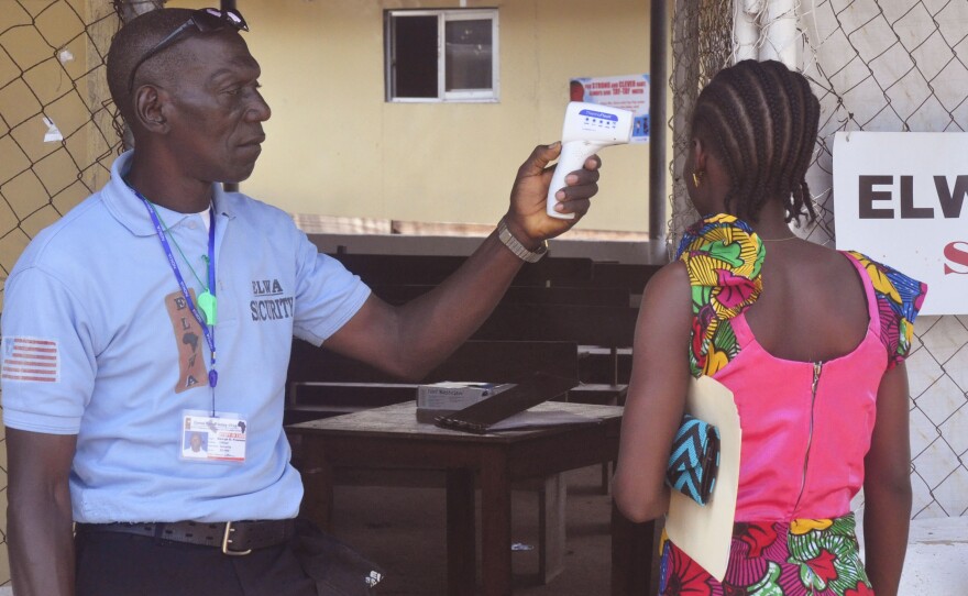 A relative of a boy who tested positive for Ebola in Liberia last week gets her temperature taken as she enters the clinic where he was being treated.