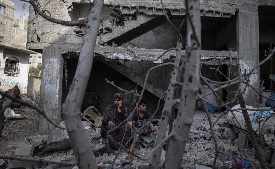 A Palestinian woman sits with her son in front of her destroyed house in the town of Beit Hanoun, northern Gaza Strip, to which she returned following a cease-fire reached after an 11-day war between Gaza's Hamas rulers and Israel.