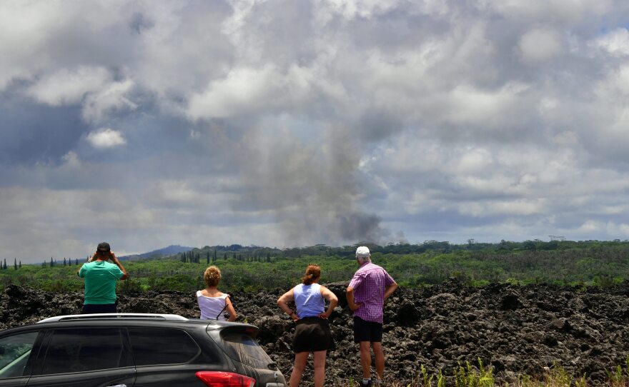 People stop on the side of the road to view a plume of smoke rising over Leilani Estates on Sunday.