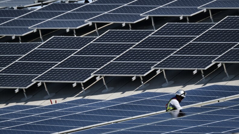 A worker helps to install solar panels onto a roof in the Van Nuys section of Los Angeles, Aug. 8, 2019. 