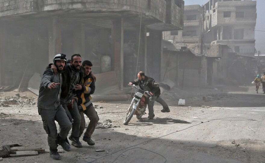 Volunteers from the Syrian Civil Defense, often known as the White Helmets, help an injured man in Hamouria during Syrian government shelling earlier this month.