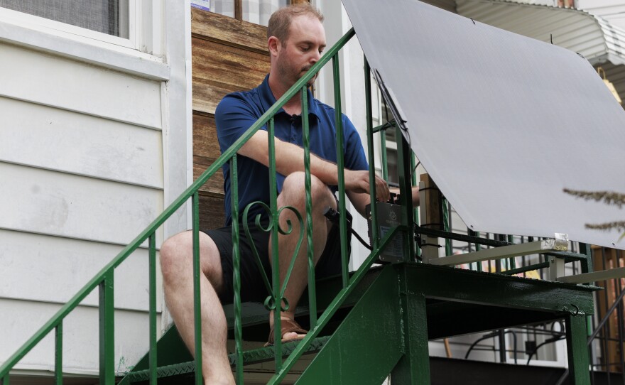 Craig Keenan installs a plug-in solar panel on his back steps last August in Baltimore.