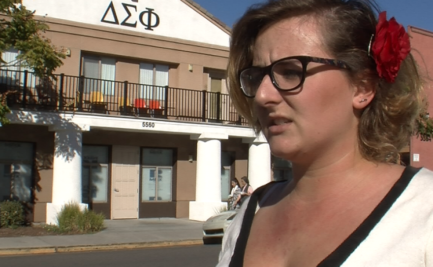 San Diego State University student Jordan Busse stands in front of the fraternity house balcony where she says men waved sex toys at her and others marching to raise awareness about rape on campus, Nov. 24, 2014.