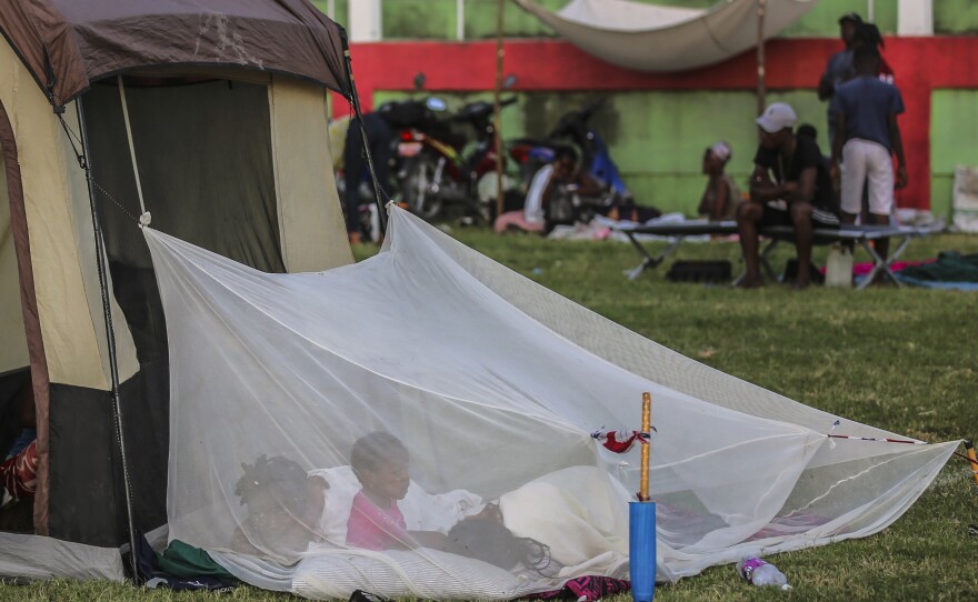 <strong>Sun., Aug. 15:</strong> A family wakes up inside a mosquito net tent after spending the night at a soccer field in Les Cayes, Haiti.
