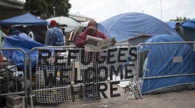 A migrant at reads a newspaper at a camp at the El Chaparral Border Crossing, in Tijuana, Mexico, Wednesday, May 2, 2018.
