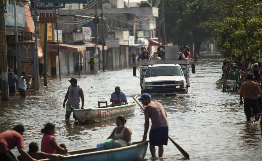 Residents make their way through a flooded street in Villahermosa, Mexico, on Nov. 11, 2020. Rising seas contribute to more damaging floods from storms and tides.