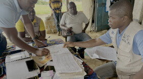 Genesis Whegelee (right, in vest) has been a community health worker for Last Mile Health in Rivercess County, Liberia, since 2018. He visits households to keep an eye on sick children, pregnant moms and anyone with a problem that needs diagnosing.
