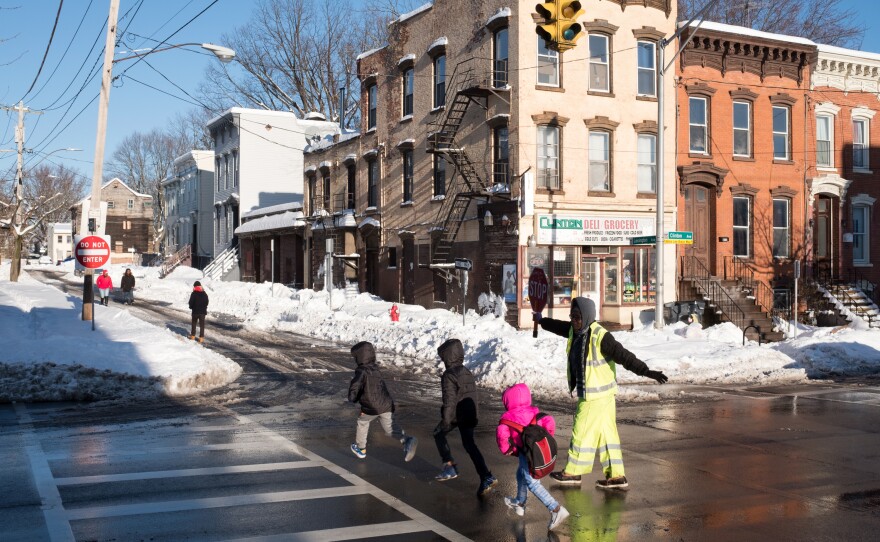 Children cross the road into Albany's West Hill neighborhood. While the neighborhood is close to the state Capitol building, many streets have boarded-up homes with red signs posted by the fire department. The signs indicate that there is potential the buildings could collapse.