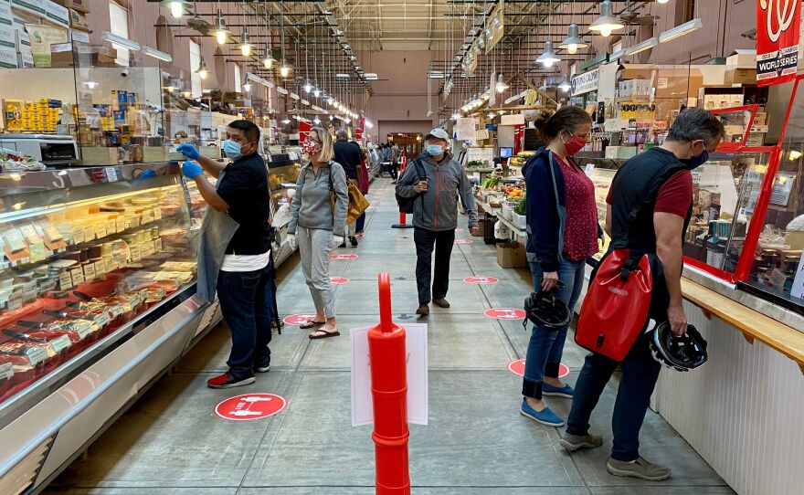 Shoppers wear masks at Eastern Market in Washington, D.C., on May 17. An NPR/PBS NewsHour/Marist poll finds that most Americans think it will take at least six months to return to normal daily life.