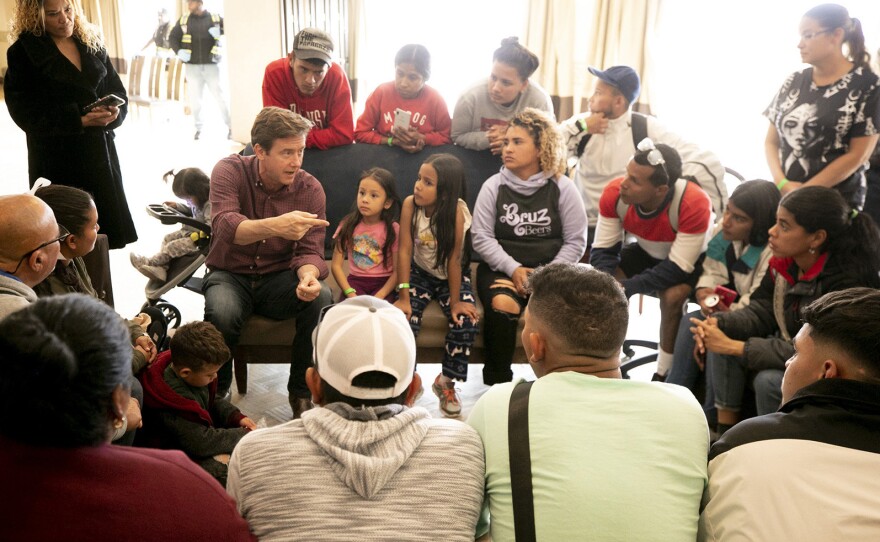 Denver Mayor Mike Johnston speaks with a group of migrants, many of whom are living outside, in a hotel run by the city. Nov. 18, 2023.