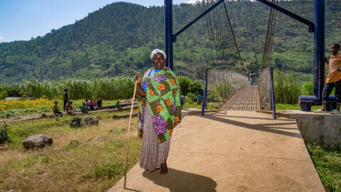 Naomi Nibishaka crosses the newly constructed pedestrian bridge over a river. She's on her way to see her son and grandchildren, who live in a settlement on the other side.