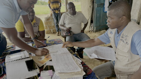 Genesis Whegelee (right, in vest) has been a community health worker for Last Mile Health in Rivercess County, Liberia, since 2018. He visits households to keep an eye on sick children, pregnant moms and anyone with a problem that needs diagnosing.
