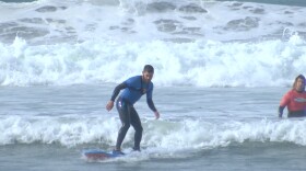 Oklahoma tourist Michael Richichi stands up on his first try surfing in Mission Beach, Jan. 19, 2016.