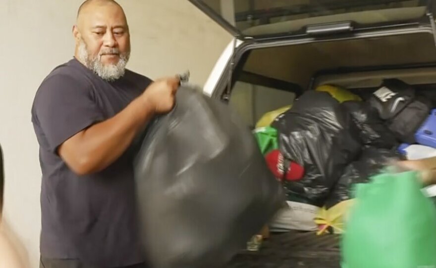 In this image taken from video, Deputy President of the Tonga Australia Chamber of Commerce Koniseti Liutai unpacks relief donations for Tonga from a vehicle Wednesday, Jan. 19, 2022, in Sydney, Australia. During an interview with the Associated Press Thursday, Jan. 20, 2022,