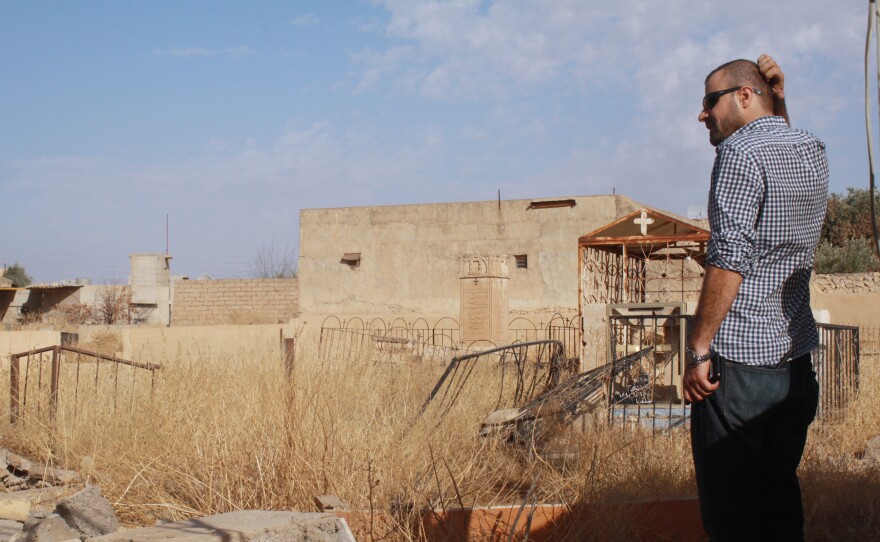 Taher Bahoo stands in a damaged graveyard in his home village of Karamlesh.