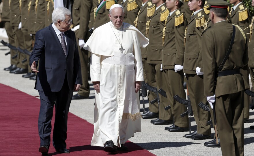 Pope Francis and Palestinian President Mahmoud Abbas review troops as they arrive at the presidential palace in the West Bank town of Bethlehem.