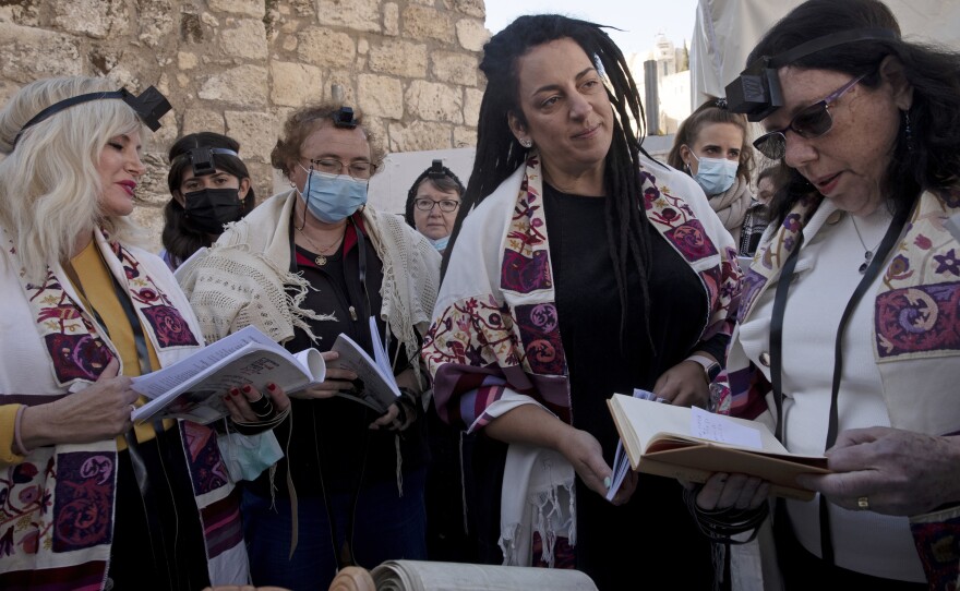 Members of Women of the Wall gather around a Torah scroll the group smuggled in for their Rosh Hodesh prayers marking the new month, at the Western Wall where women are forbidden from reading from the Tora.