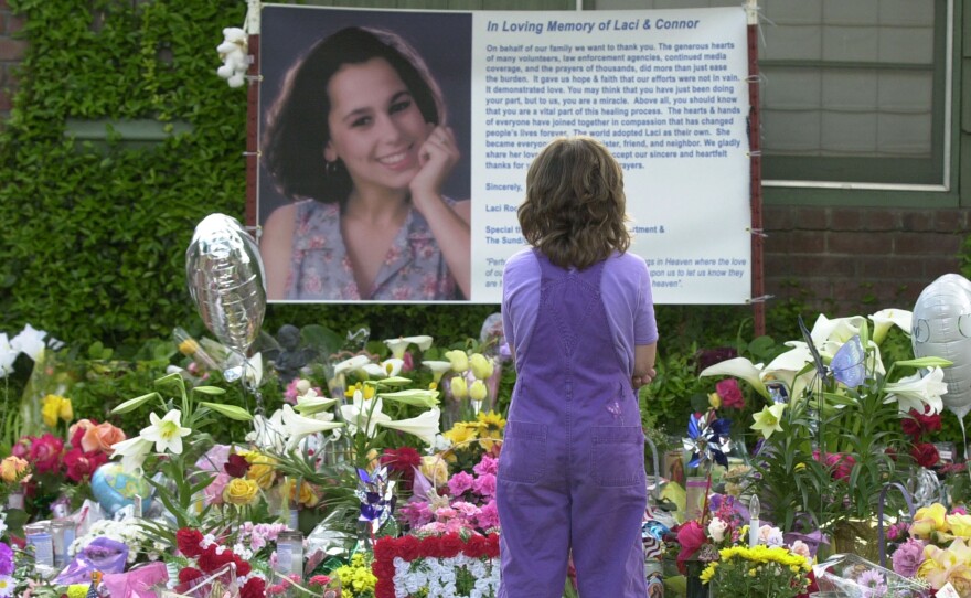 In this April 21, 2003 photo, Sarah Kellison stands in front of a memorial in honor of Laci Peterson outside the house Laci shared with her husband Scott Peterson in Modesto, Calif.